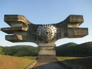 Monument to the Revolution of the People of Moslavina, a brutalist concrete sculpture with wing-like forms and a central metallic disc.