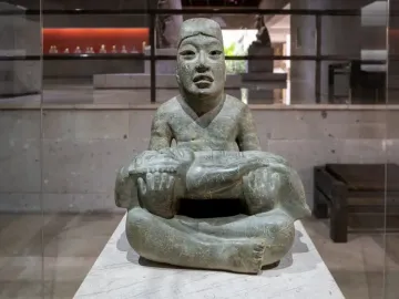 Las Limas Figurine showing a seated stone figure holding a smaller jaguar-like figure across its lap.