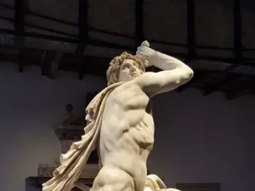 Ludovisi Gaul marble sculpture showing a man raising a sword above his head beside a collapsing draped woman on a circular base.