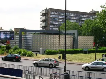Michael Faraday Memorial beside a road, with a light-colored patterned surface and nearby landscaping.