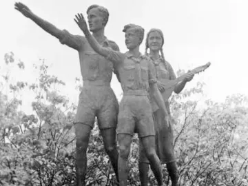 Youth Monument showing three young figures on a stone pedestal, with one male figure saluting and a female figure holding a lute-like instrument.