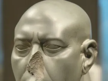 Berlin Green Head sculpture of a bald face with closed eyes and a damaged nose.