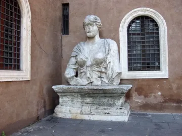 Madama Lucrezia stone bust mounted on a pedestal beside barred windows.