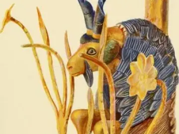 Ram in a Thicket sculpture with a gold head and legs, dark curved horns, and a blue-black and gold body leaning against a tree-like structure.