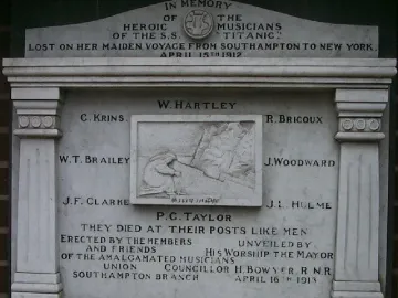 Titanic Musicians\' Memorial stone plaque mounted on a brick wall with inscriptions and a central relief carving.