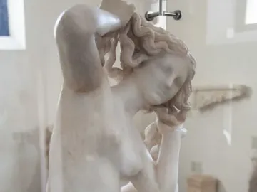 Crouching Venus marble sculpture of a crouching nude female figure displayed in a glass case