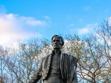 Bronze statue of General José Gervasio Artigas standing outdoors with a hat in his left hand.