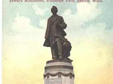 William Henry Seward monument in Volunteer Park, with a bronze statue on a tall stone pedestal in a grassy area.