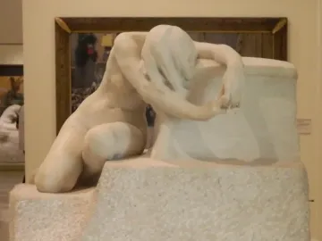 Desolation, a white marble sculpture of a nude kneeling figure with bowed head and long hair draped over the face.