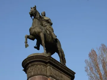 Monument to Mykola Shchors, a bronze equestrian statue on an ornate pedestal against a blue sky.