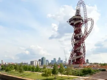 Orbit Tower rising beside a canal, with its twisting steel structure reflected in the water.