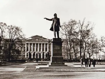 Pushkin statue stands before the Mikhailovsky Palace with a classical facade and trees in the background.
