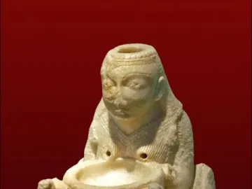 Lady of Galera figurine showing a seated carved figure holding a basin, flanked by two smaller winged figures.