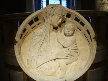 Madonna del Perdono stone relief showing a woman holding a child with halos and a decorative border