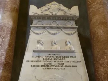 Monument to the Royal Stuarts with white marble figures, busts, and a Latin inscription between red marble columns