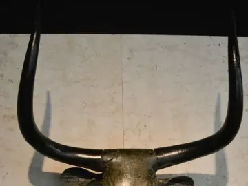 Toros de Costitx bronze bull head sculpture with curved horns and stylized features against a light wall.