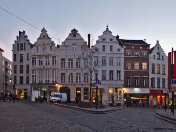 L\'Envol sculpture on a cobblestone square in Brussels, with historic buildings and a bare tree in the background.