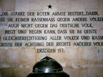 German inscription on a tiled wall at the Soviet War Memorial Schönholzer Heide, with a black star above it and the top of a dark dome at the bottom.
