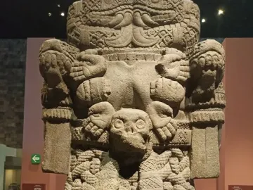 Coatlicue stone statue with a skull-like head, clawed feet, and carved symbolic patterns