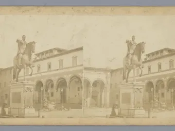 Ferdinando I de\' Medici equestrian statue on a tall pedestal in a stone-paved plaza with historic arched porticos and scattered people nearby.
