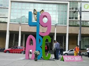 Antimonumento 49 ABC standing on a city plaza, with a pink \