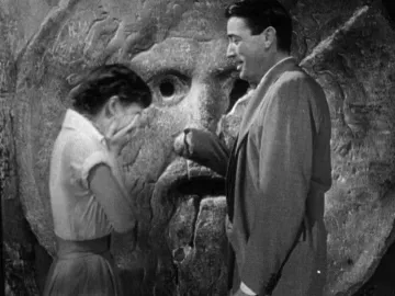 Bocca della Verità stone mask with a man placing his hand in the mouth beside a woman covering her face