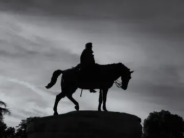 Silhouette of the Monument to General Martínez-Campos, an equestrian statue on a stone base against a cloudy sky.