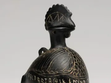Viterbo Rooster, a dark bird-shaped vessel with etched feather patterns and an inscription around the lower body.