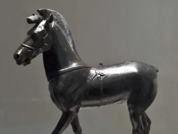 Bronze horse statuette from Olympia shown in profile on a pedestal.