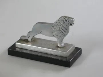 Silver-colored metal lion figure on a two-tiered rectangular base, facing right.