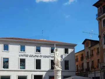 Monumento dell\'Indipendenza statue of a draped female figure holding a spear in front of a historic brick building.
