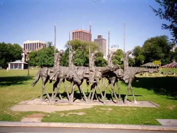The Partisans sculpture shows several gaunt figures riding skeletal horses and holding tall poles in a grassy urban park.