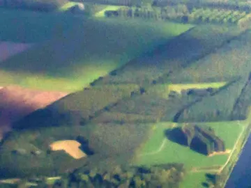 Aerial view of The Green Cathedral surrounded by green fields and a waterway.