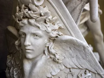 Close-up of Angelo Nocchiero, a white marble youthful figure with curly hair, a leafy crown, and a carved wing.