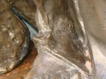Close-up of Eustache de Saint Pierre’s bronze foot on a textured base, with bare toes beneath heavy drapery.