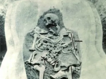 Human-shaped sarcophagus with a partially excavated skeleton inside, shown with measurement lines and angles.