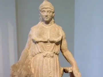 Unfinished marble Lenormant Athena statue with a helmet and long tunic, holding a large coiled object.