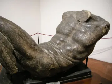 River God sculpture showing a reclining male torso and upper legs with a rough, textured surface.