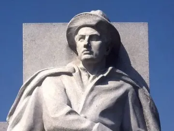 Soldiers\' Monument stone statue of a man in a wide-brimmed hat and long coat holding a sword or rifle hilt.