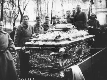 Alexander Nevsky reliquary casket on a flatbed vehicle with uniformed men standing nearby.