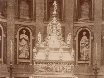 Arca di San Domenico inside a vaulted chapel, with a towering carved funerary monument, railings, and candelabras