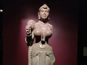 Didarganj Yakshi standing stone statue holding a fly-whisk, with necklaces, a headdress, and a draped lower garment.