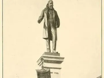 Albert Pike Memorial with a large statue of a bearded man atop a multi-tiered stone pedestal, with a smaller seated bronze figure below.