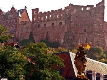 Kornmarkt Madonna standing above tiled rooftops with Heidelberg Castle in the background