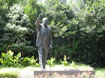 Bronze Winston Churchill statue raising his right hand in a V for victory gesture and holding a cane.