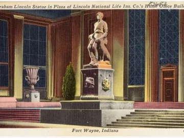 Abraham Lincoln: The Hoosier Youth bronze statue of a seated young Lincoln holding a book, with an axe and a dog beside him.