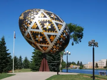 Vegreville pysanka egg sculpture with geometric black, gold, and white patterns outdoors.