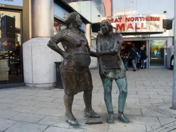 Monument to the Unknown Woman Worker with two weathered bronze female figures, one holding a basket and the other incorporating a rotary phone and keyboard.