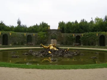The Enceladus Fountain shows a golden reclining figure emerging from dark rocks in a formal garden pond.