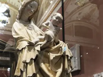 Krumlov Madonna sculpture of a robed woman holding a child in a museum case.